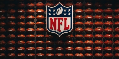 NFL badge in front of American footballs stacked on a shelf